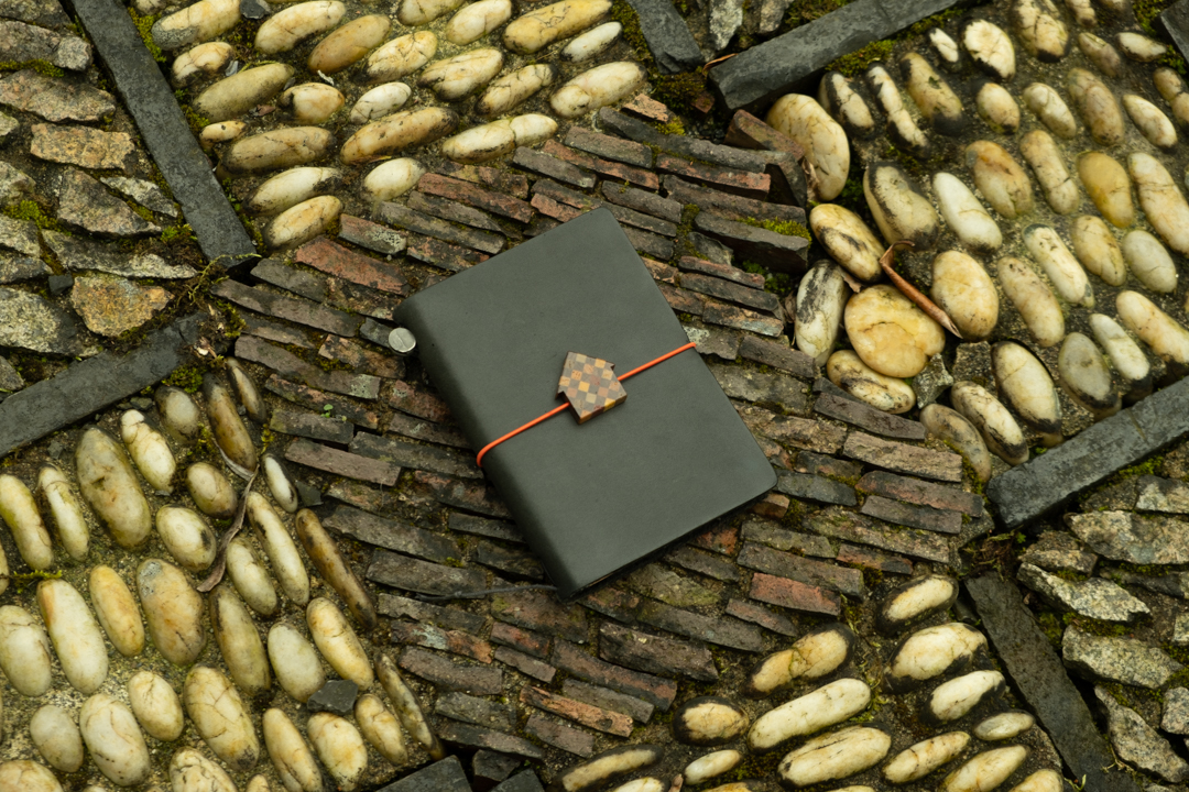TRAVELER'S notebook Passport Size with Luthier House Charm on the ground. 