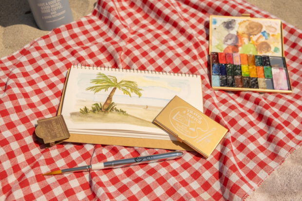 Painting with TRAVEL & SKETCH SPIRAL RING NOTEBOOK on a picnic blanket at the beach.