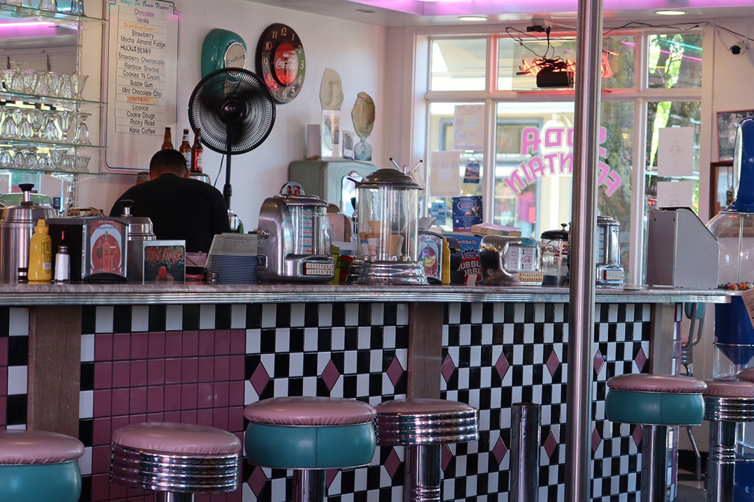 An old-fashion soda fountain diner with pink and teal decor.