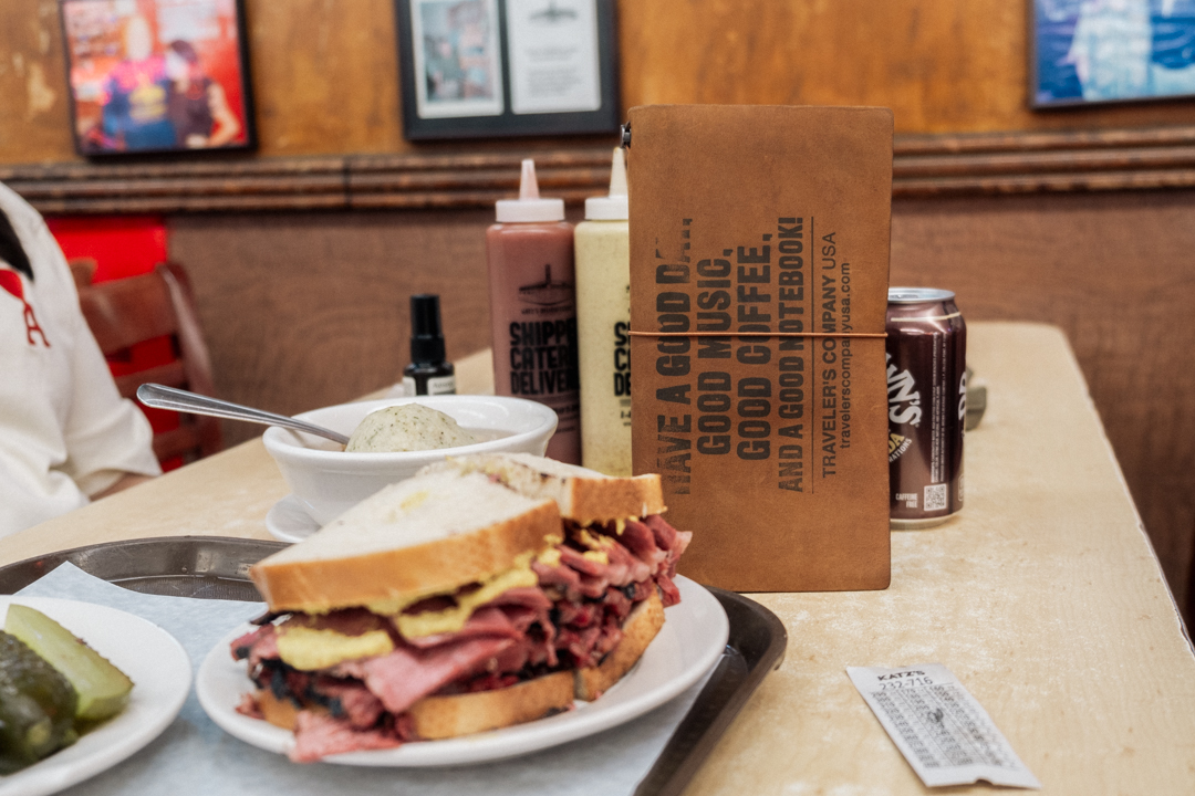 Pastrami sandwich from Katz's Deli beside TRAVELER'S notebook.