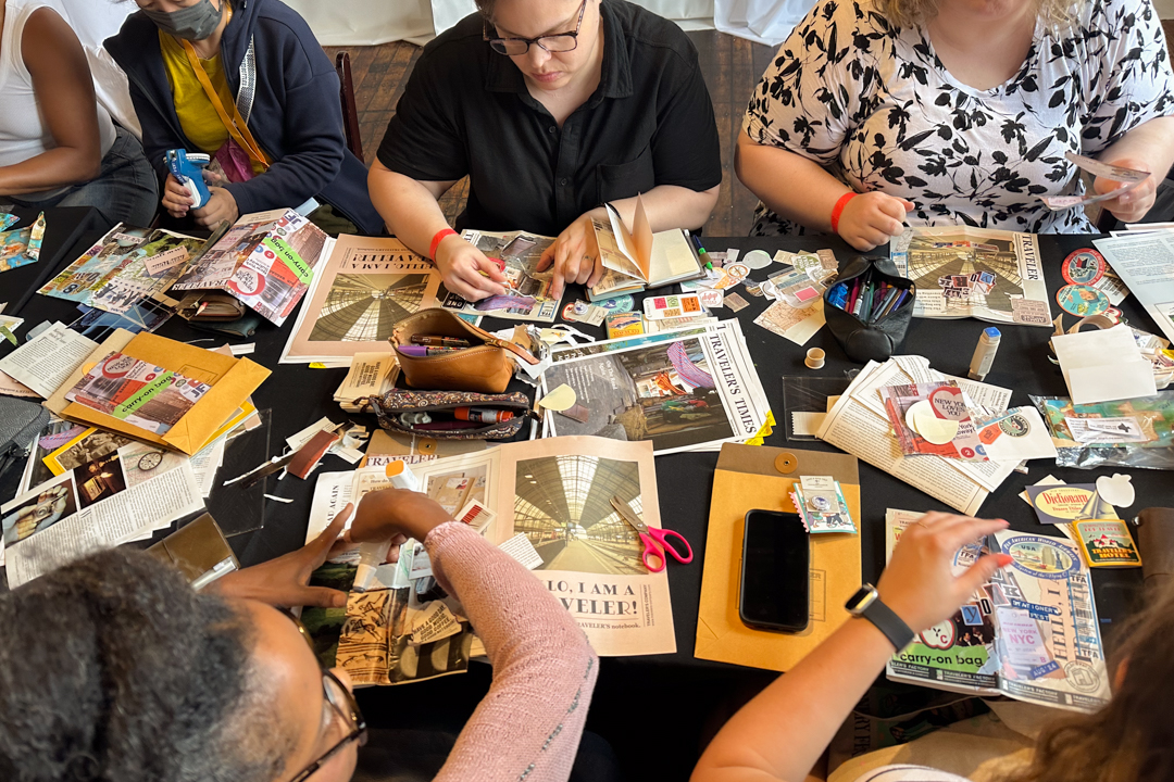 TRAVELER'S notebook users at a workshop journaling, collaging, and creating art together at a white table.