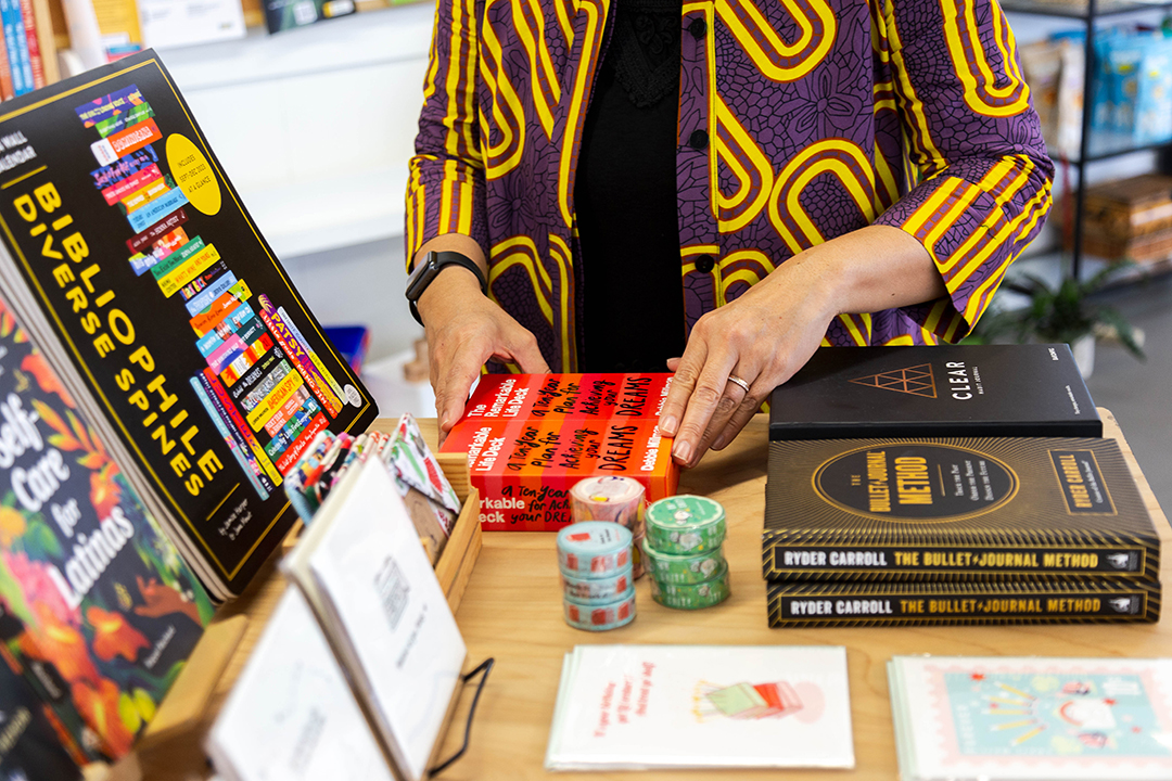 Bel Canto Books owner Jhoanna rearranging books on a table.