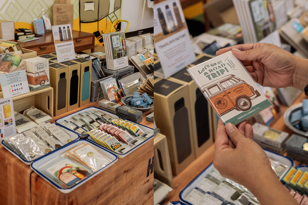 Person holding a Passport size TRAVELER'S notebook insert in front of the TRC USA Pop-Up display at the KUBO LB store.