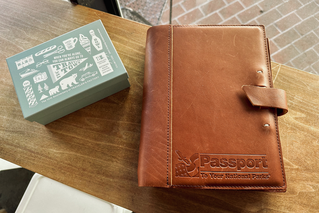 National Parks Limited Edition Passport book beside metal tin on wooden table.