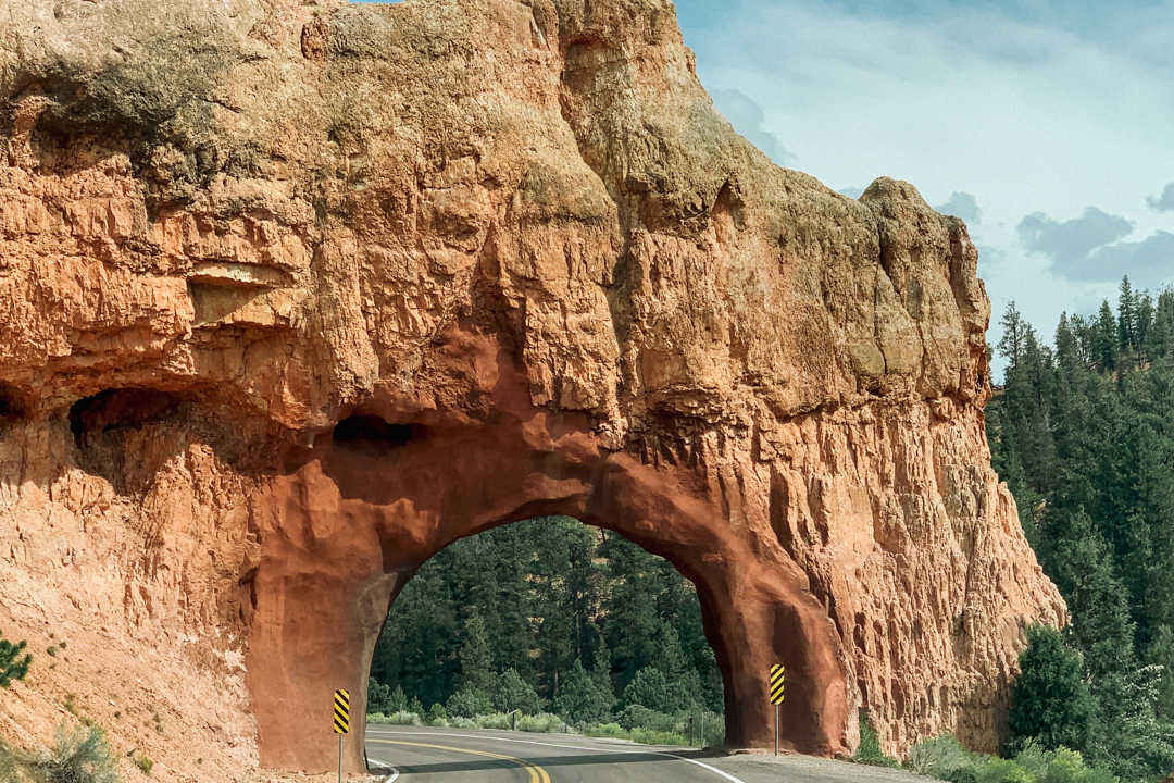 Rock bridge which has a passage for cars with a road passing through the rock bridge.