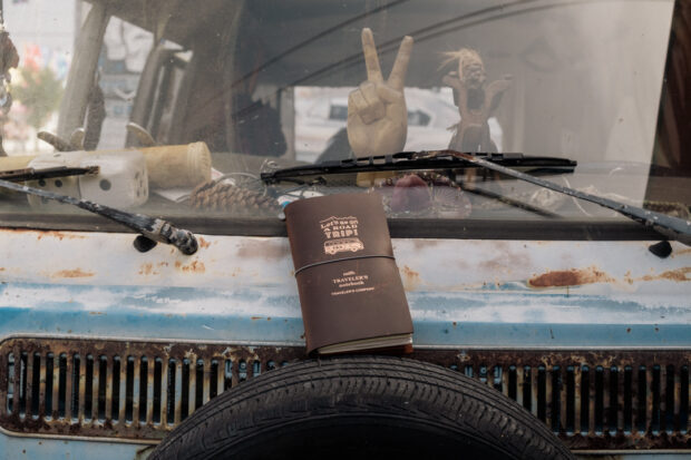 a TRAVELER'S notebook setting on a vintage volkswagen.