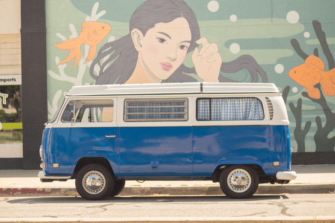 Blue Volkswagen van parked in front of a mural.