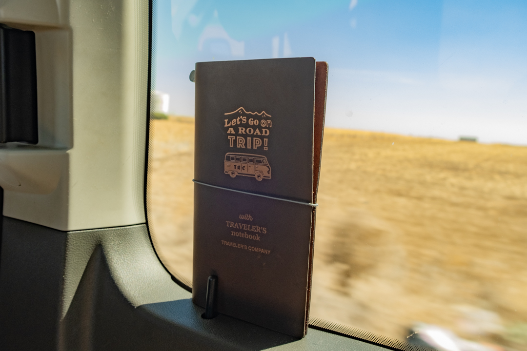 TRAVELER'S notebook USA Road Trip leaning against a van window.