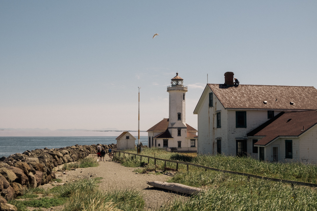 A lighthouse against the calm water and skyline.