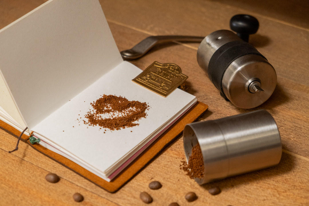 PORLEX Grinder and ground coffee on a TRAVELER'S notebook.