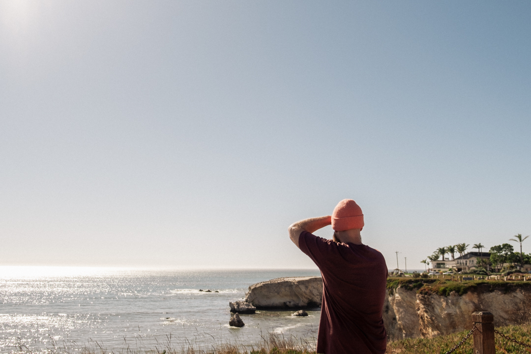 Person looking into the distance in front of water and cliff.