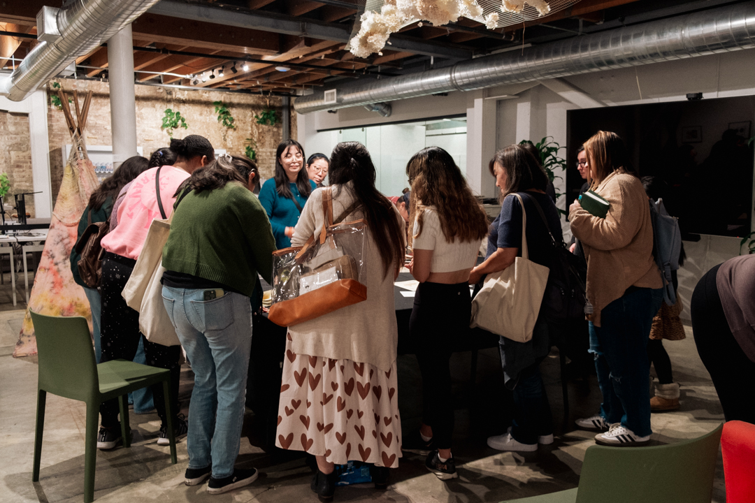 People huddled over a table filled with ink stamps, with people stamping their notebooks.