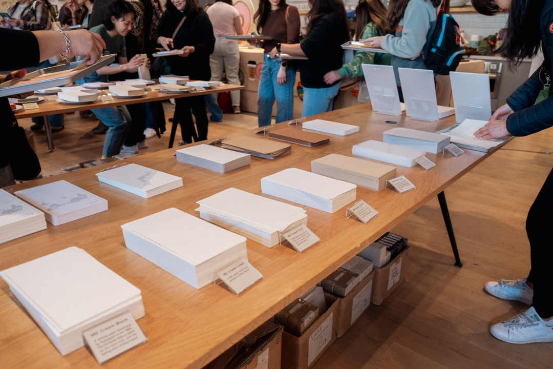 Stacks of different papers on wooden table with labels in front of each stack.