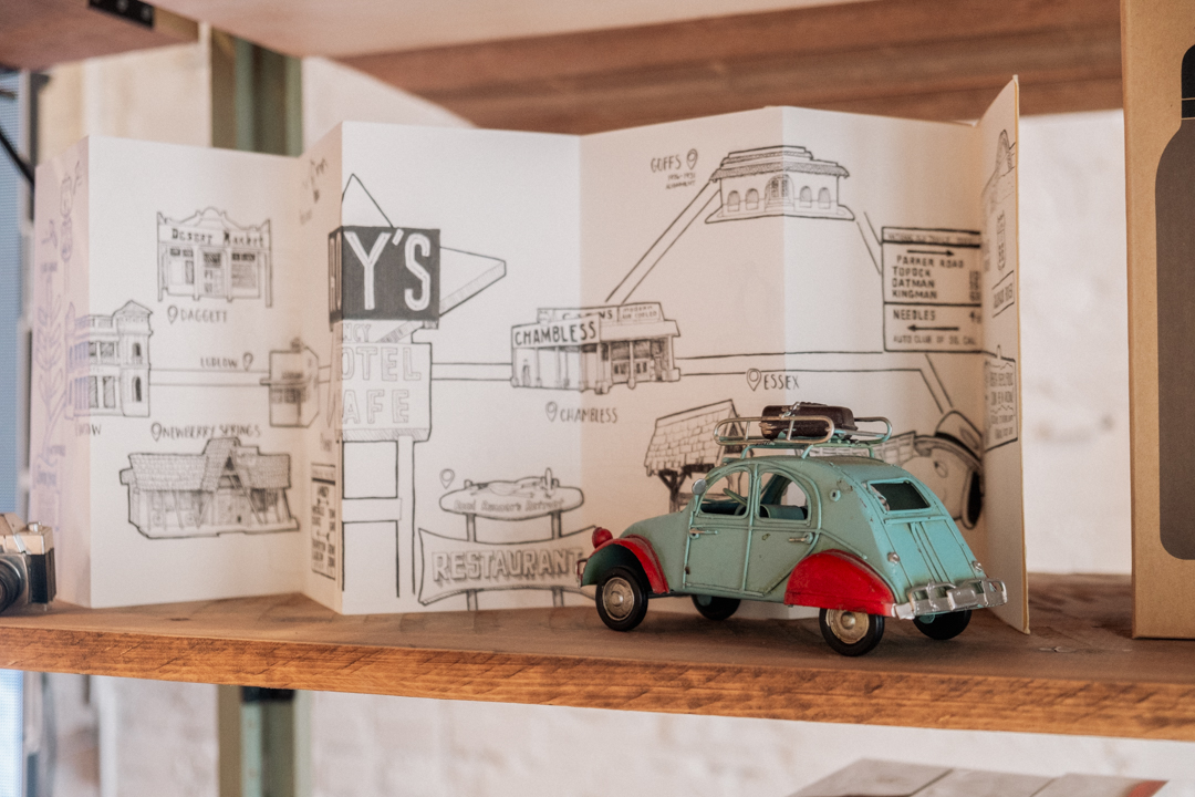 Accordion notebook open with different road trip illustrations beside a toy car.