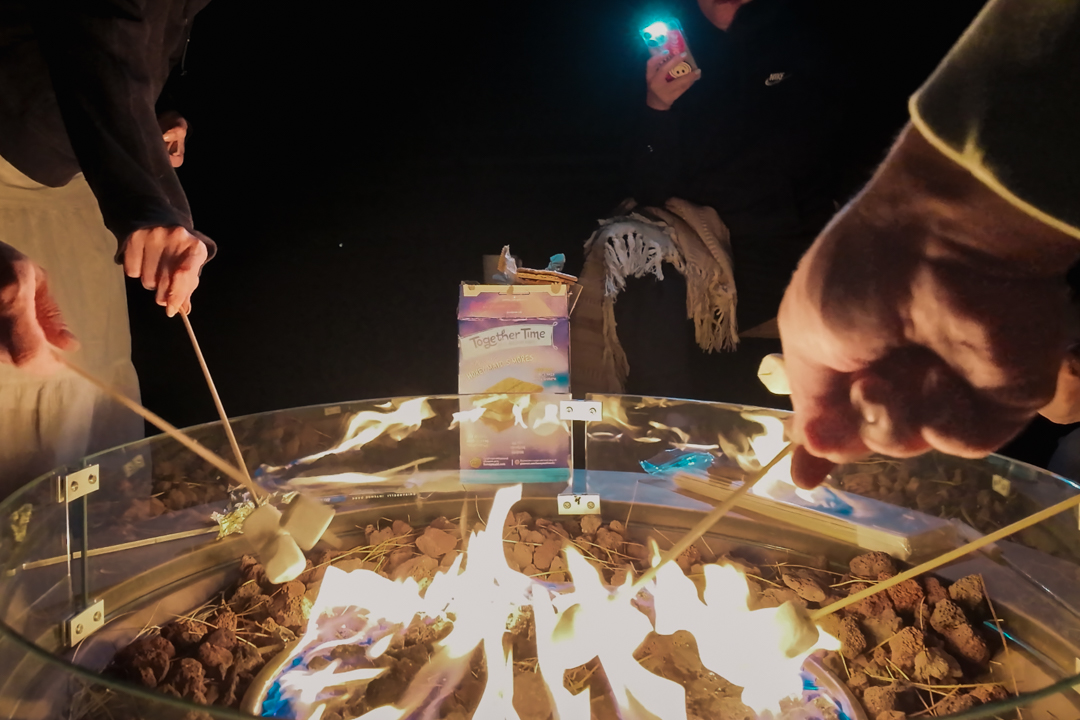 People roasting marshmallows at an outdoor fire pit.