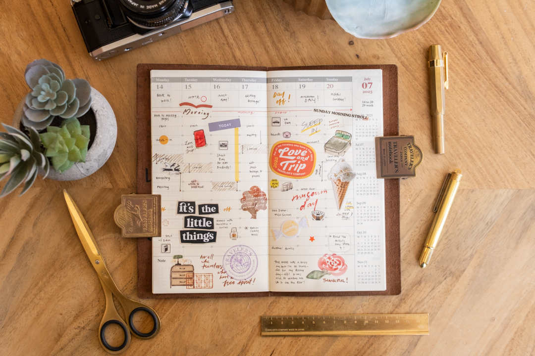 2025 Second Half Diary on a desk surrounded by brass pen, rulers, and scissor.
