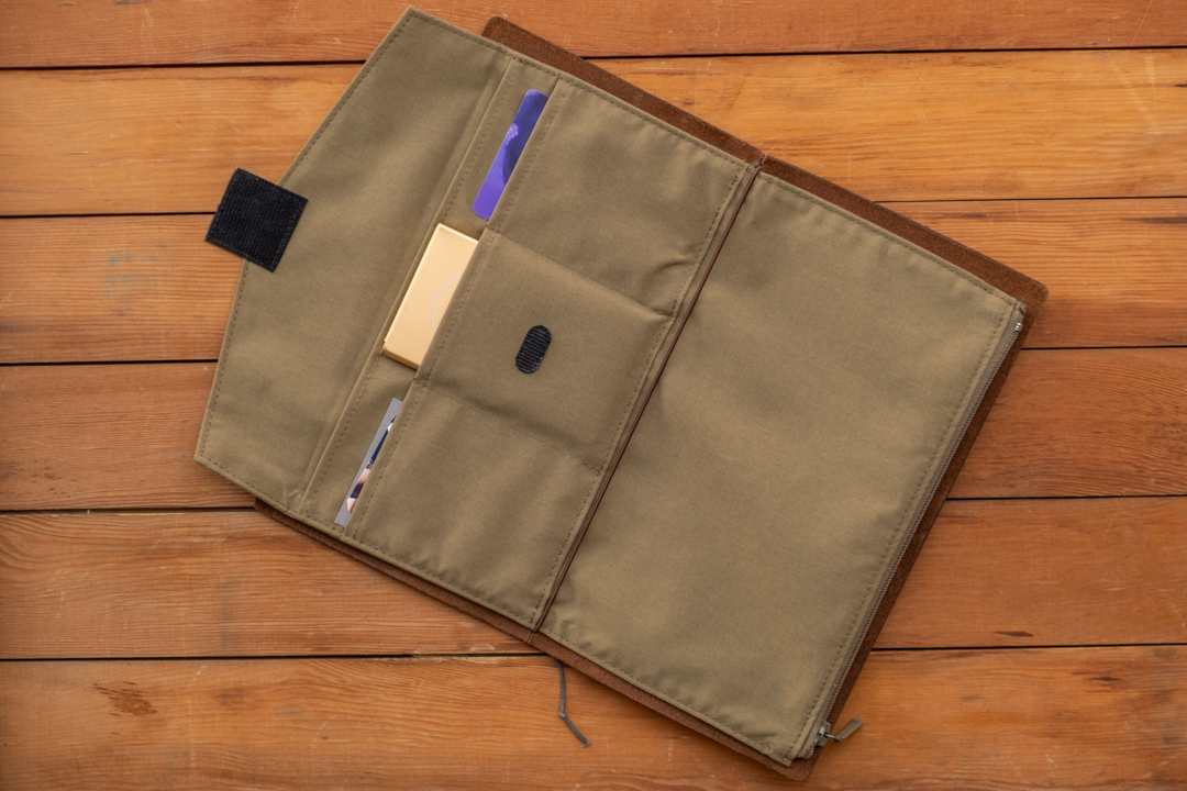 TO&FRO Zipper Case in Olive in a Regular Size TRAVELER'S notebook on a wooden table.