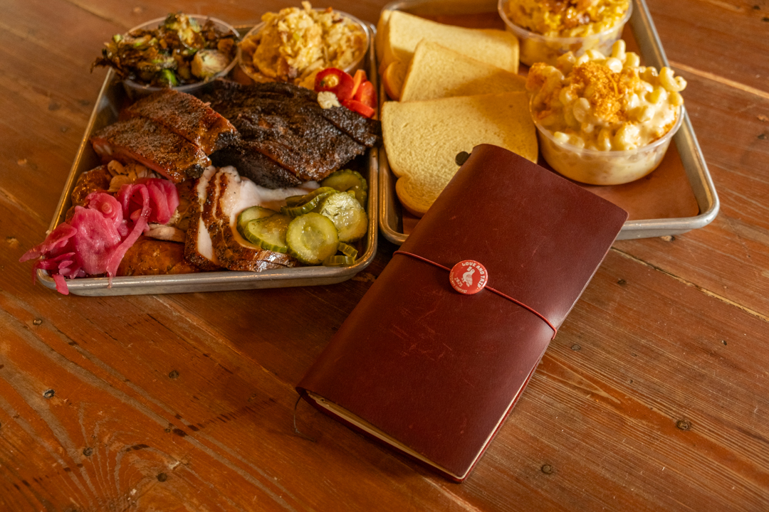 Red TRAVELER'S notebook beside southern-style BBQ.