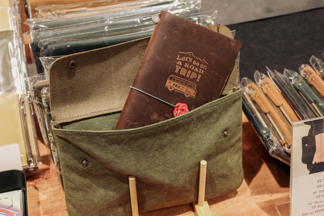 A brown TRAVELER'S notebook resting inside a green pouch.