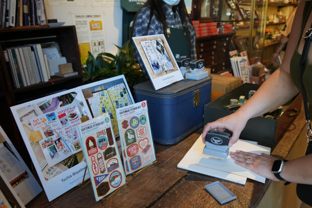 A person stamping in a TRAVELER'S notebook at the Stamp Caravan.