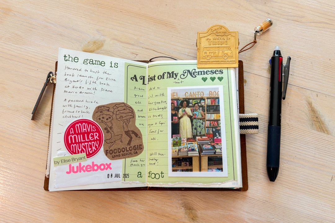 A brown passport TRAVELER'S notebook open to a travel journal spread beside a pen on a wooden table.