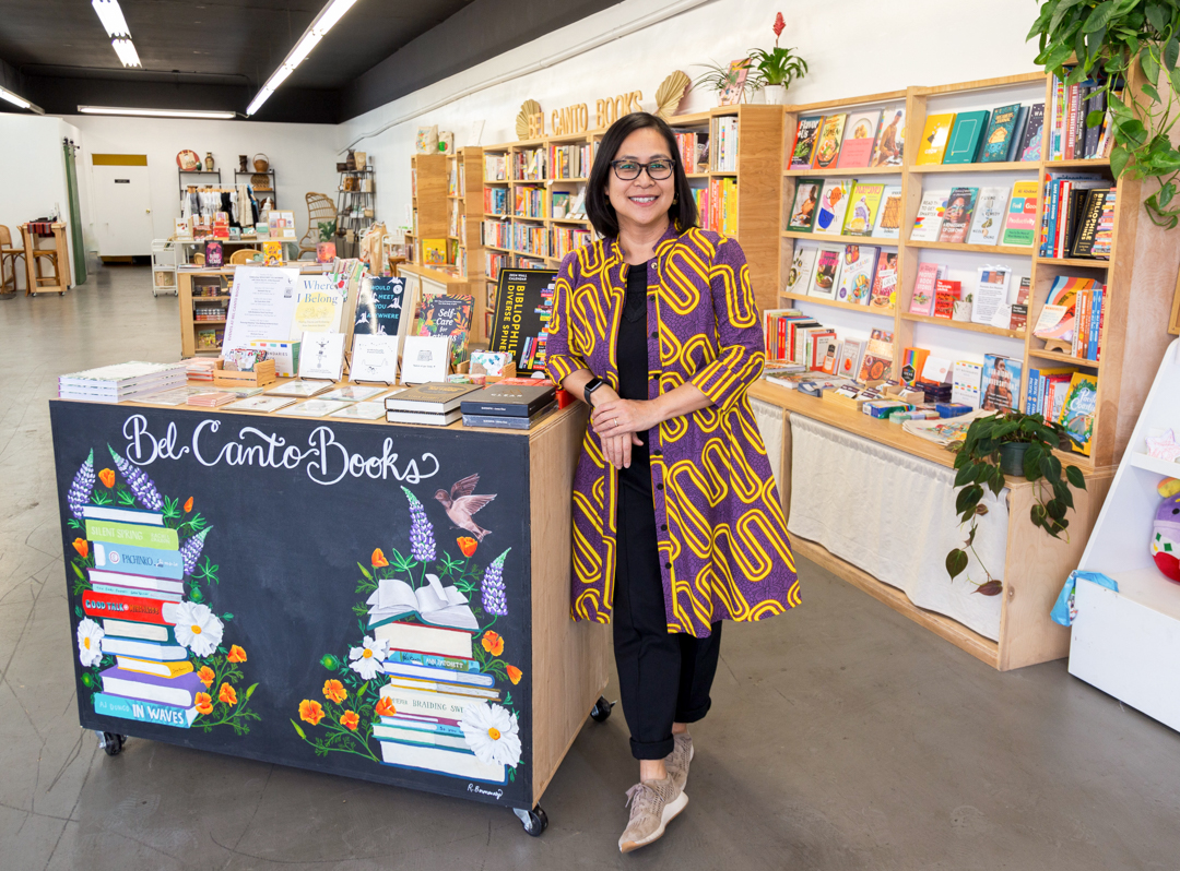 Jhoanna Belfer, owner of Bel Canto Books posing near a book display in the KUBO LB store in Long Beach, California.