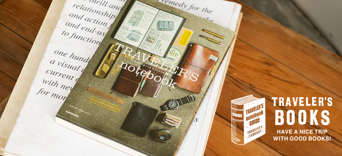 TRAVELER'S notebook OFFICIAL GUIDE on a wooden table.