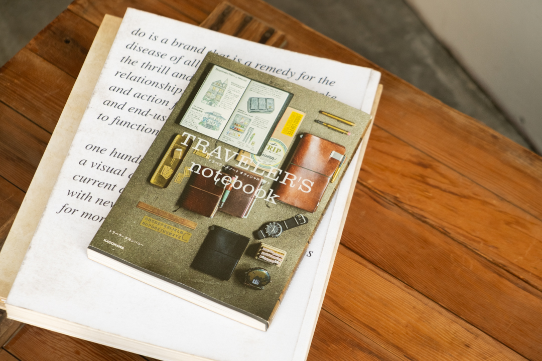The TRAVELER'S GUIDE book propped up on top of other large books on a wooden table.