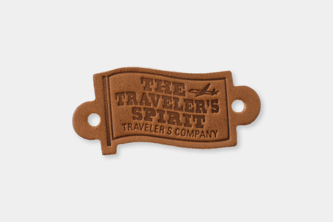 A leather tag with the words "THE TRAVELER'S SPIRIT" engraved on it.