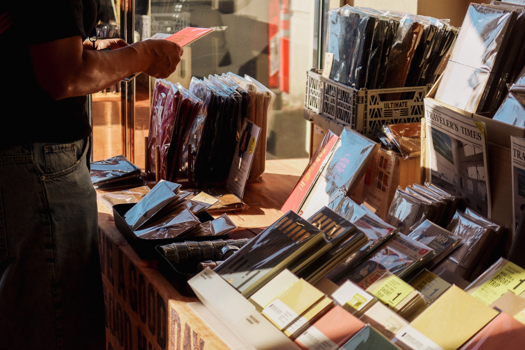 A person shopping for TRAVELER'S COMPANY and TRAVELER'S FACTORY Original items at the TRC USA table at the SF Pen Show.
