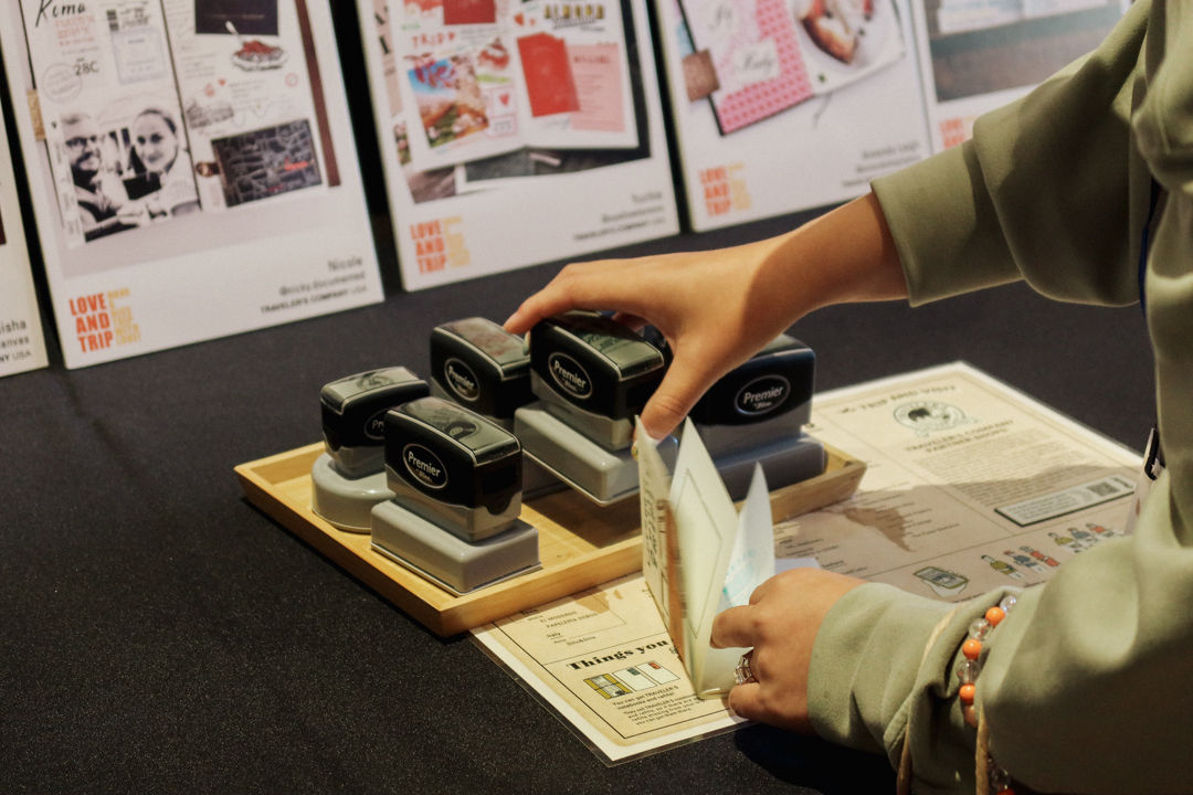 A person using the TRC Stamp Caravan stamps at the TRC USA table at the SF Pen Show.