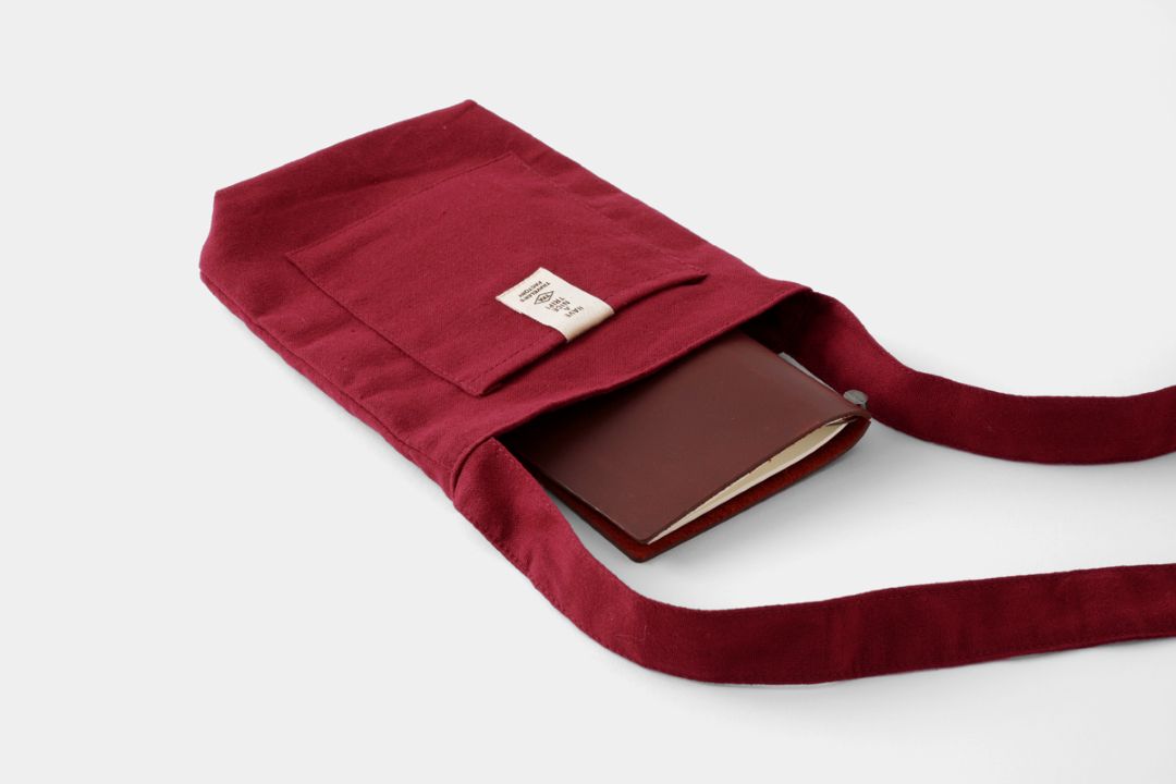 A red sacoche with a TRAVELER'S notebook inside.