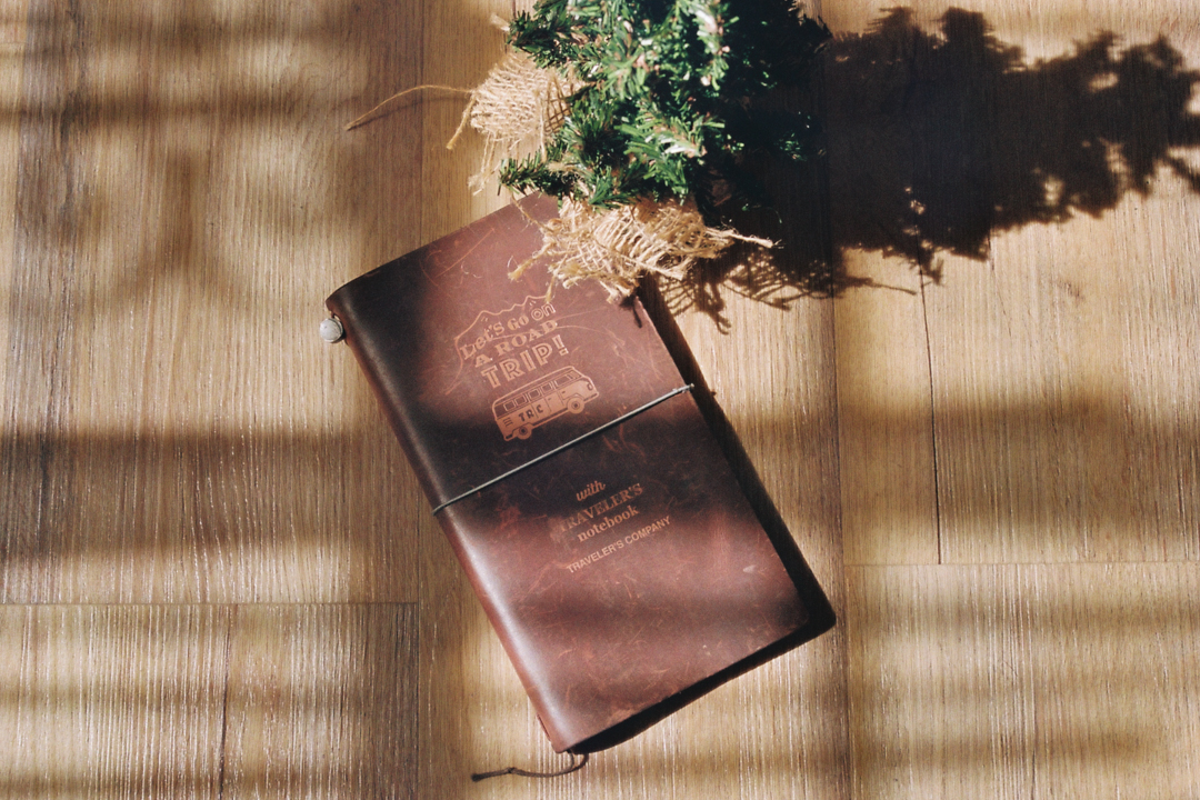 warm afternoon light on a TRAVELER'S notebook ROAD TRIP next to a christmas tree fixture.