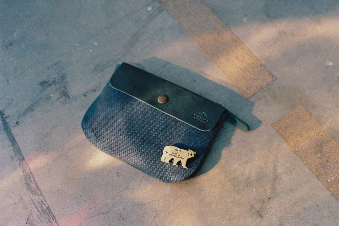 TF Canvas pouch in SS size with a brass badge bear pinned on it.