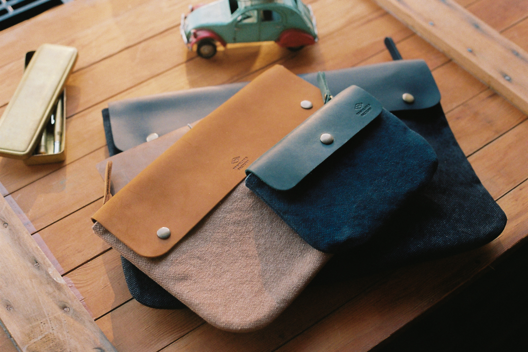 TRAVELER'S FACTORY Original leather zipper cases in a pile.