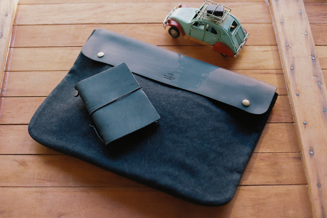TF Canvas pouch in L size in black with a TRAVELER'S notebook on top.