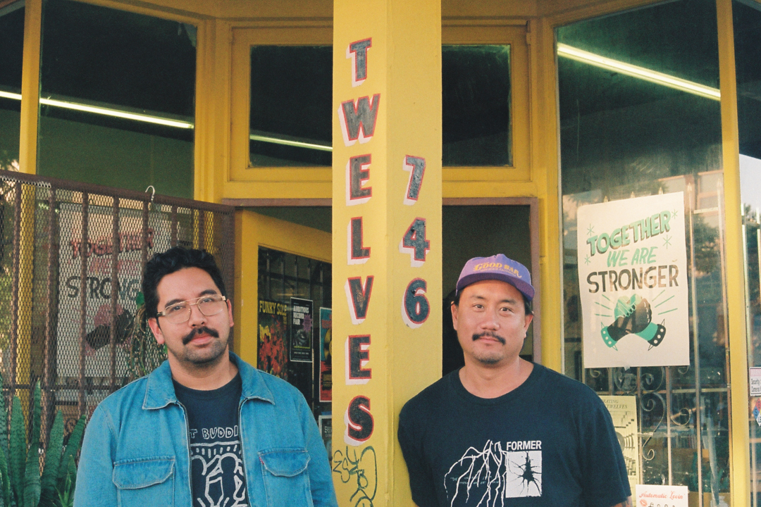 Two men named Hector and Tony stand smiling outside a store with a yellow facade. The entrance features signs, including "Twelves 746" and "Together We Are Stronger."