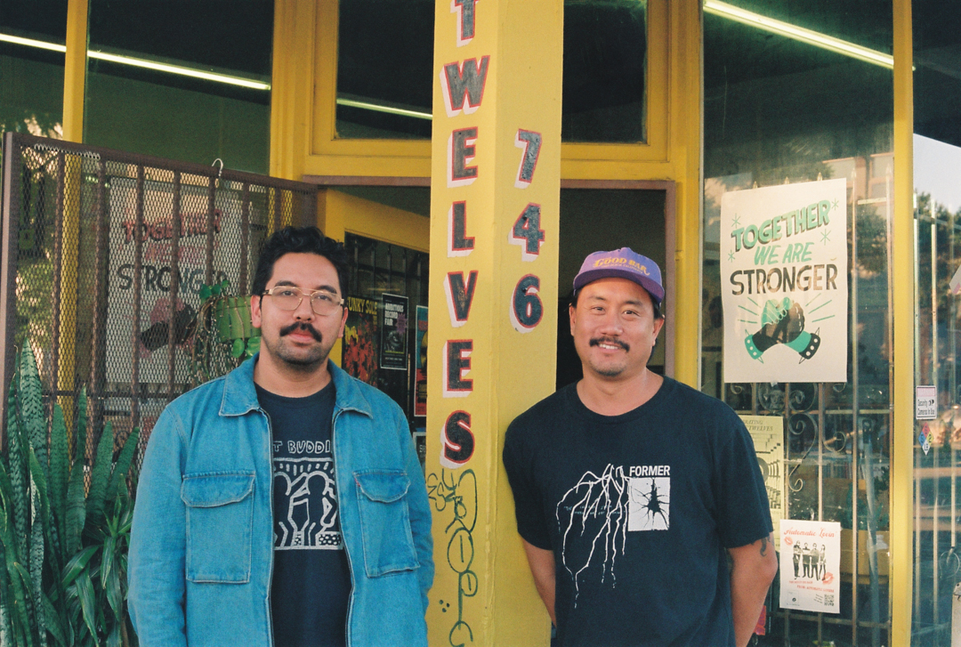 Two men named Hector and Tony stand smiling outside a store with a yellow facade. The entrance features signs, including "Twelves 746" and "Together We Are Stronger."