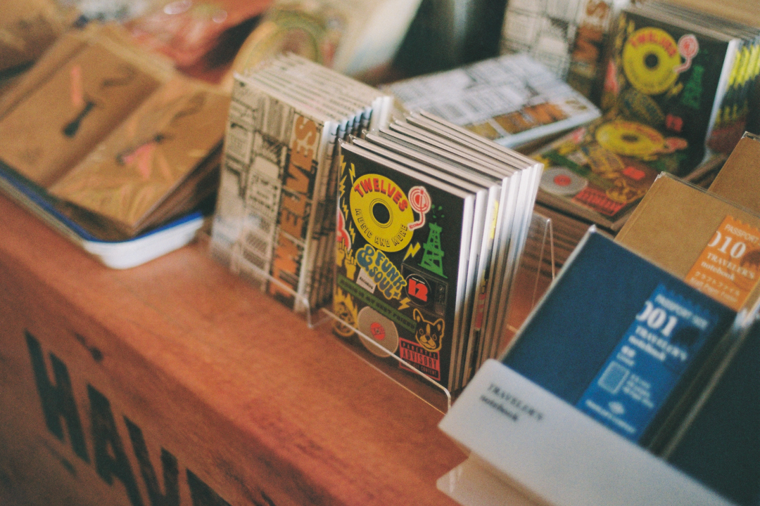 A display of colorful "sticker" and "crate" notebook inserts with vibrant designs is arranged on a wooden table, creating an artistic and retro atmosphere.