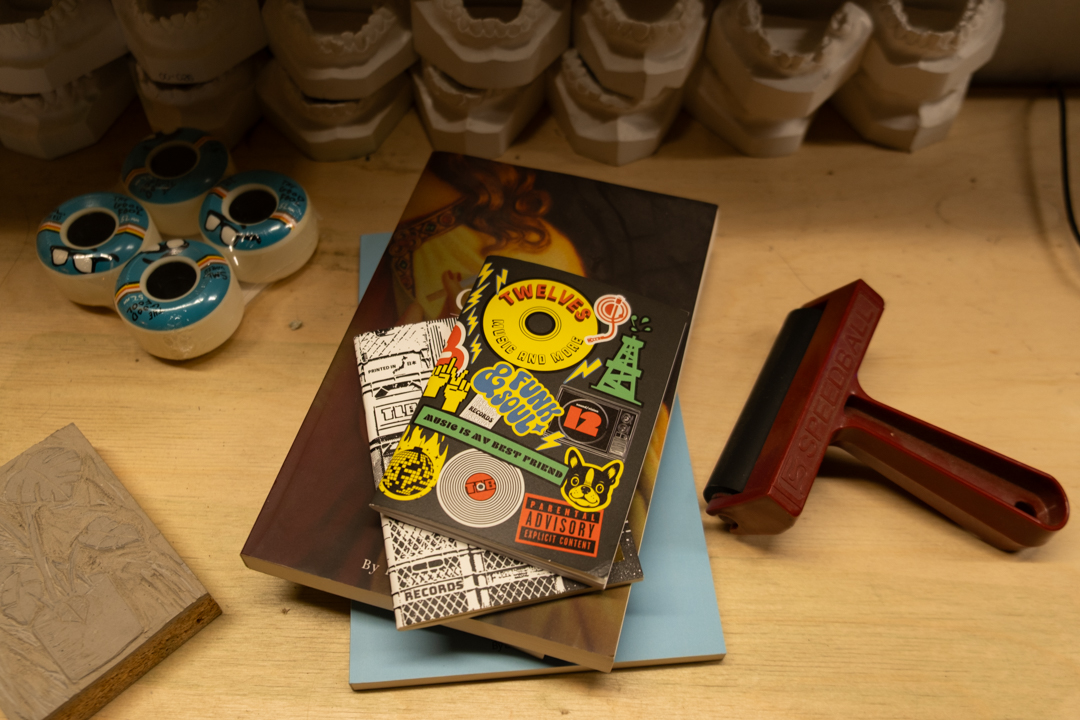 Tony Bach's TRAVELER'S notebook insert on top of his older design work, which is on a wooden table in his creative studio behind TWELVES RECORD.