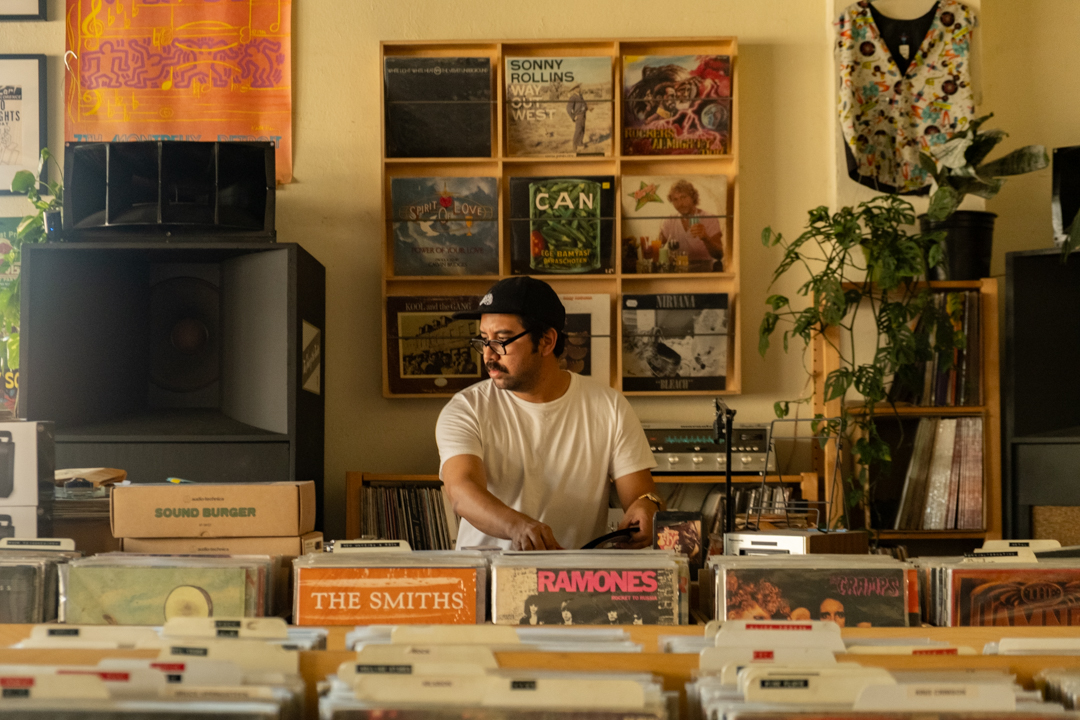 Shop owner Hector behind a DJ booth at TWELVES RECORD, where Hector is DJing.