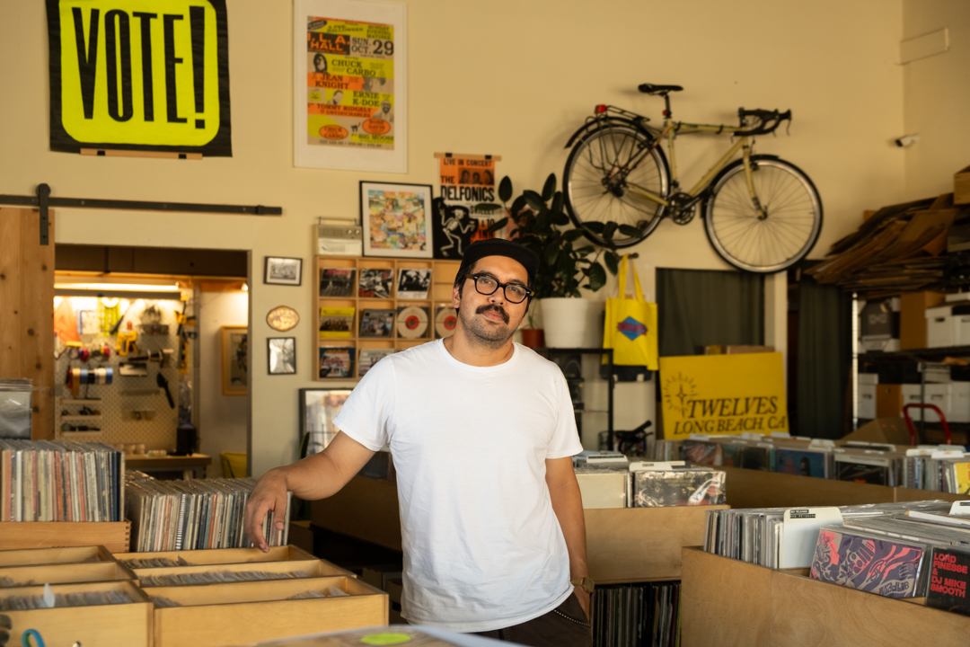 Shop owner Hector posing with the wooden record boxes in his store, TWELVES.