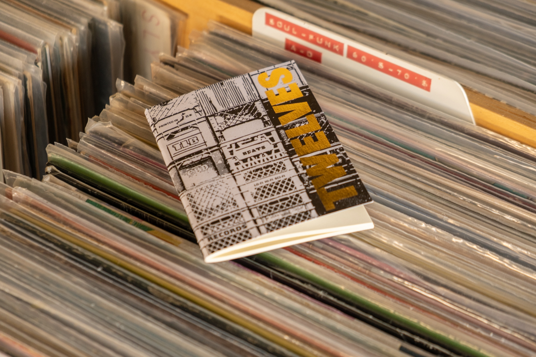TRAVELER’S notebook refill TWELVES RECORD Crate (Passport Size) placed on top of a bin filled with records.
