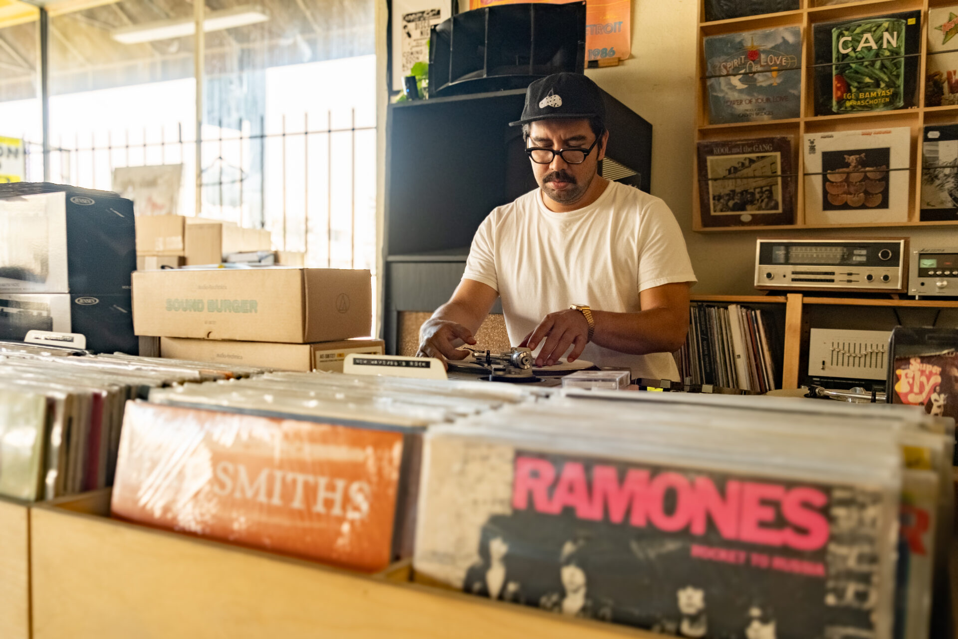 Shop owner Hector behind a DJ booth at TWELVES RECORD, where Hector is DJing.