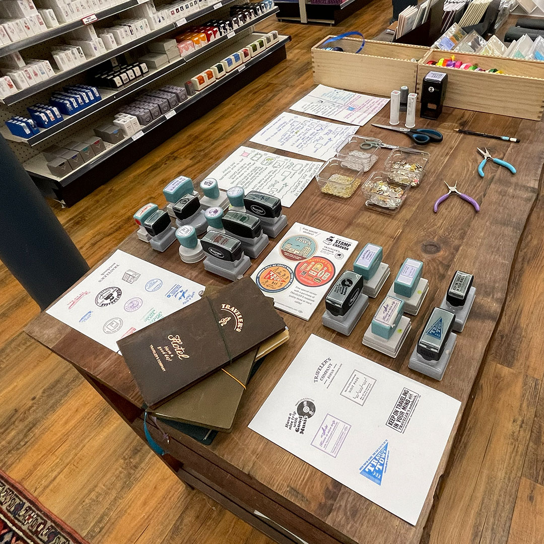 An old tool table holding TRAVELER'S COMPANY Stamp Carvan items inside Atlas Stationers.