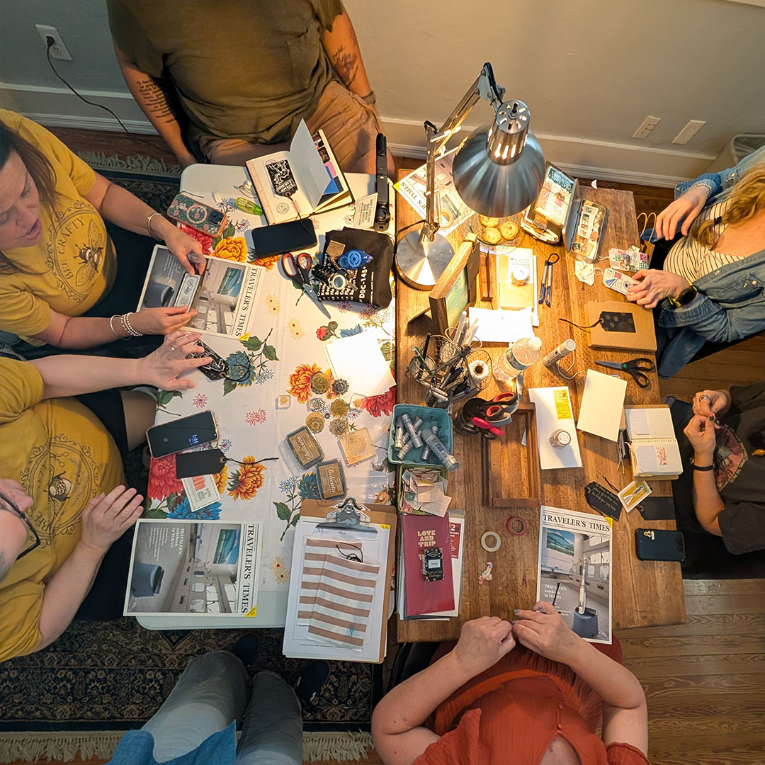 TRAVELER'S notebook fans sit around a table to create special ephemera for their notebooks.