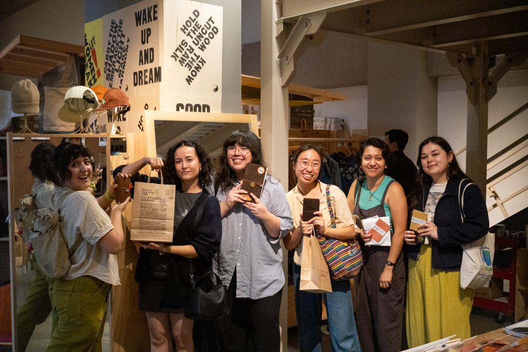 Happy shoppers posing with their purchases and new TRAVELER'S tote bags in front of the inspirational wall graphics.