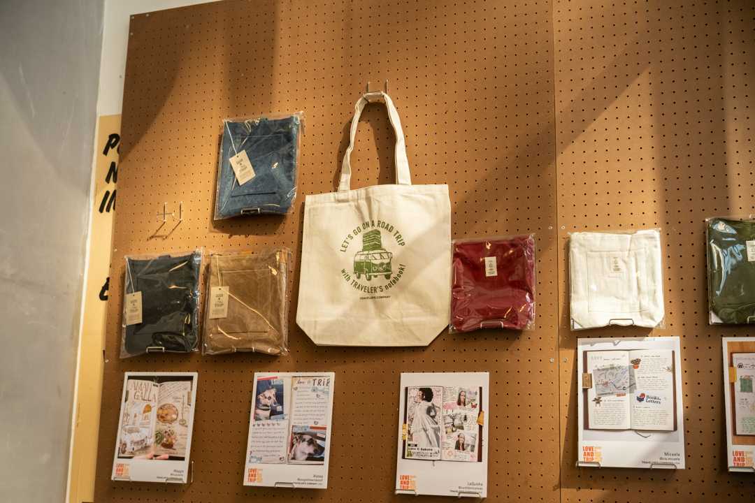 Another view of the pegboard merchandising system featuring bags, pouches, and sample journal pages from the TRAVELER'S community.