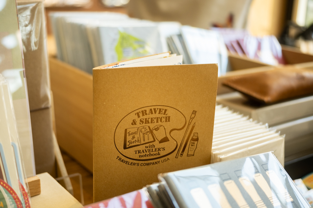 The "Travel & Sketch with TRAVELER'S notebook" accordion paper notebook insert, designed for artists and travelers on the pop-up table at HIGHTIDE STORE DTLA.