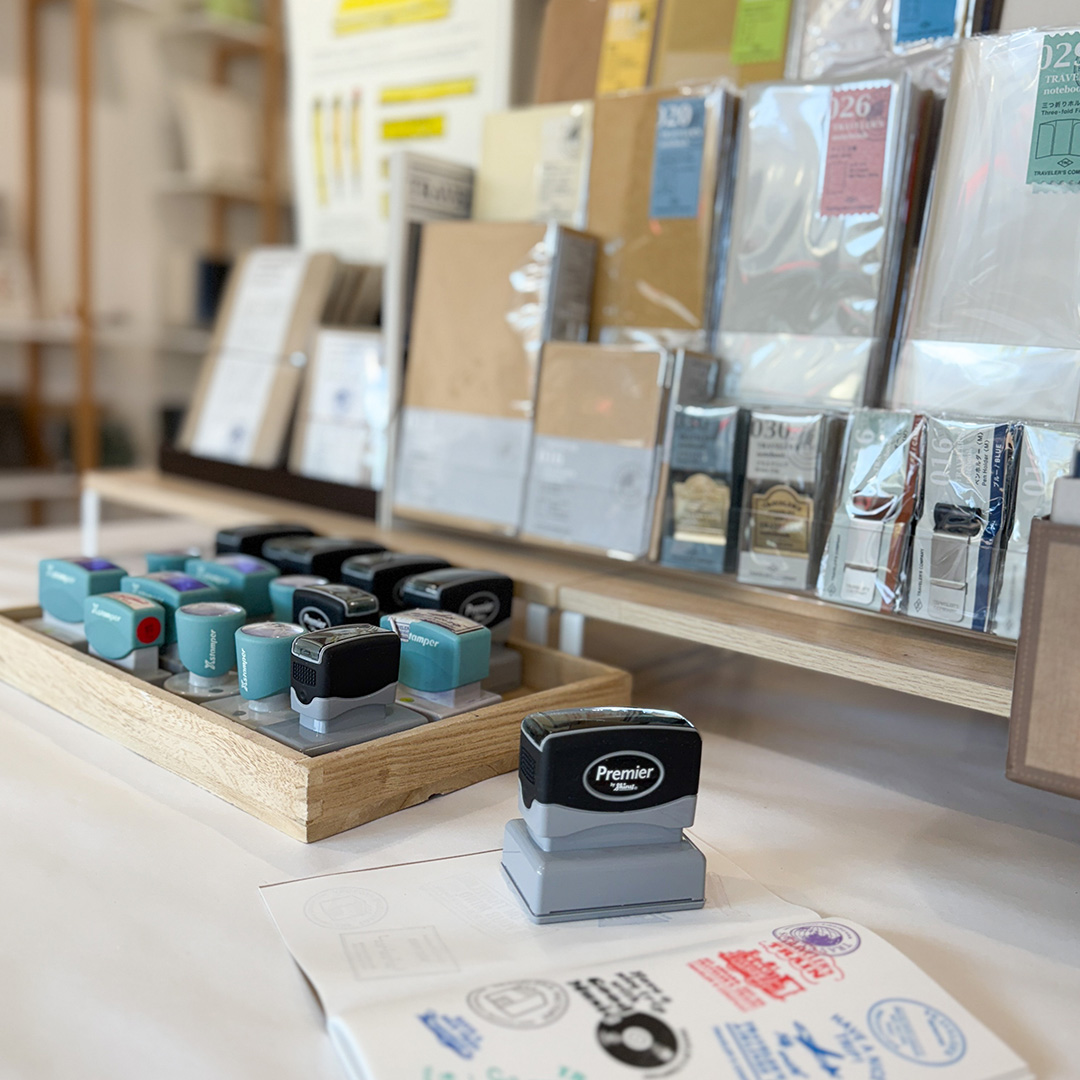 The TRC Stamp Caravan stamps are displayed neatly in front of a selection of TRAVELER'S COMPANY products.